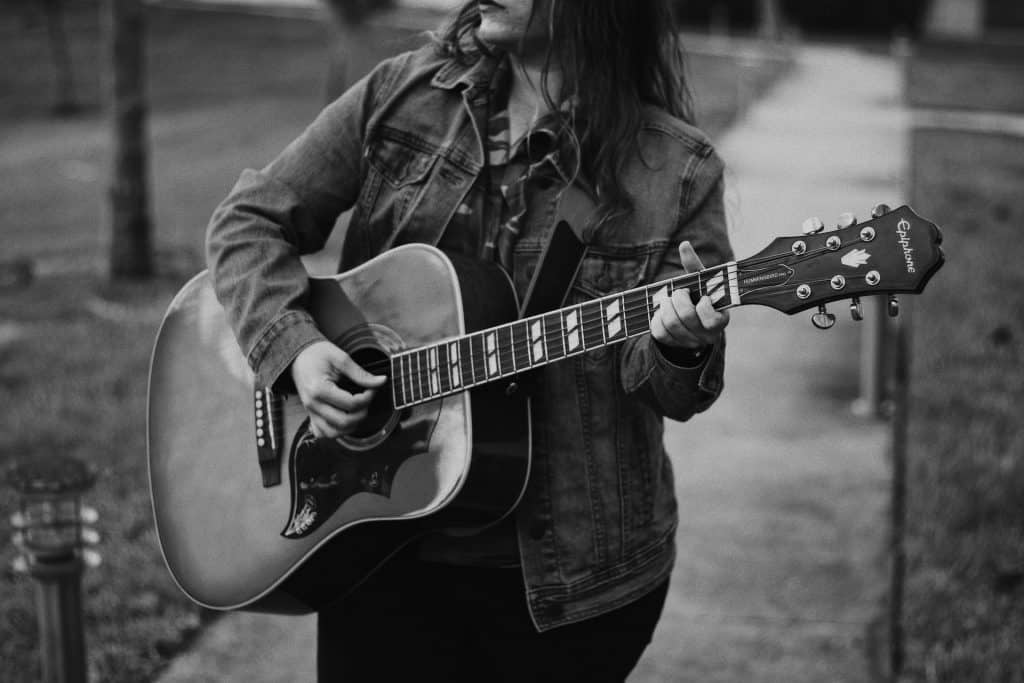 woman playing fingerstyle on acoustic guitar