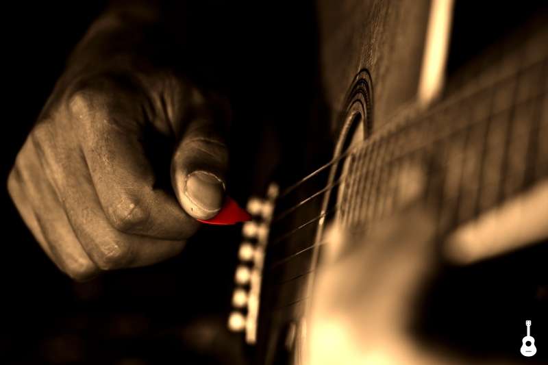 Guitarist playing with small pointed pick